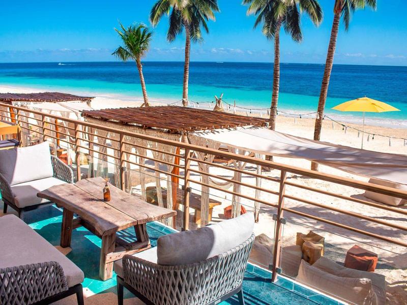 Terrazza dell'hotel con sedie e vista sulla spiaggia e palme.