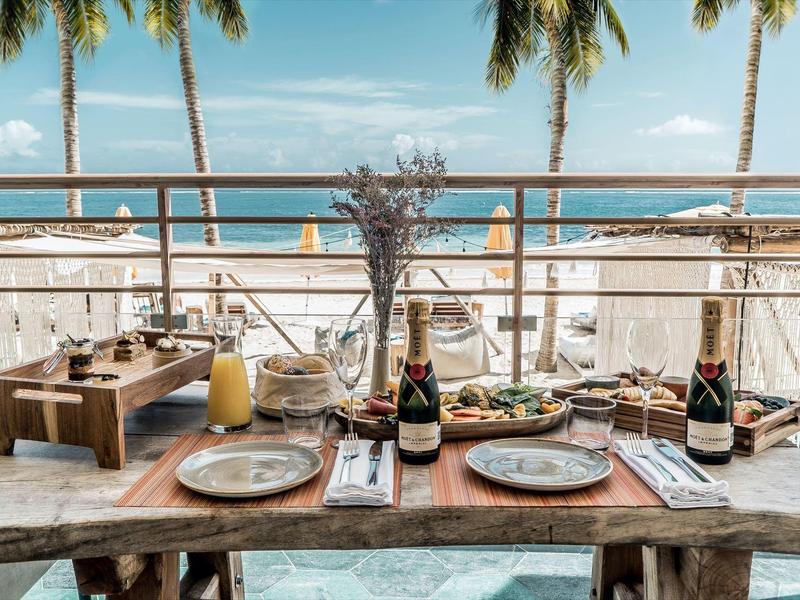 Tavola apparecchiata con vista sul mare e palme sullo sfondo.