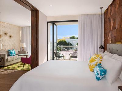 Camera d'hotel moderna con letto, decorazioni colorate e terrazza soleggiata.