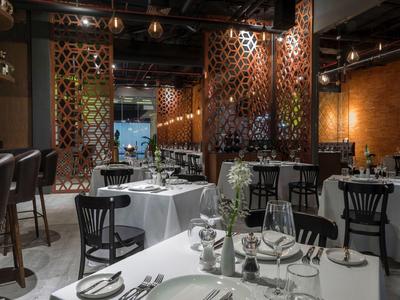 Elegantní restaurace s bílým prostřením a tmavými dřevěnými židlemi v teple osvětlené místnosti.