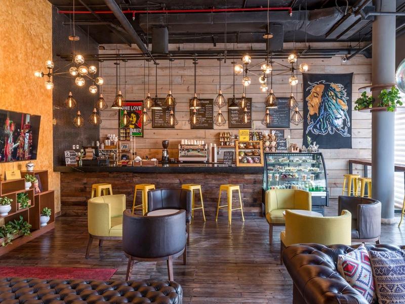 Accogliente salotto dell'hotel con poltrone, tavoli in legno e illuminazione sospesa.