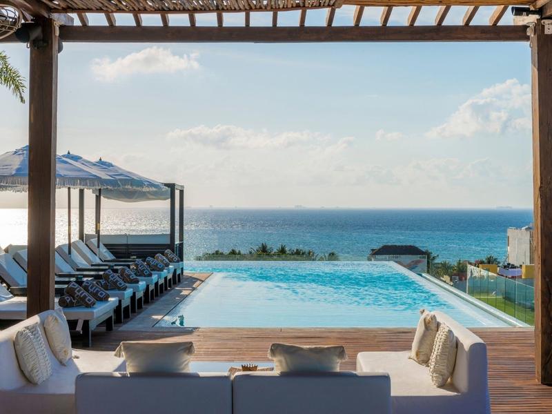 Piscina a sfioro con vista mare, posti a sedere confortevoli sotto pergolato.