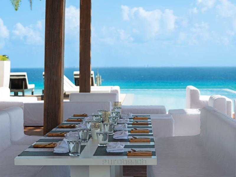 Tavolo elegante apparecchiato in ristorante sulla spiaggia con vista sull'oceano blu.