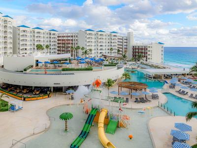 Großes Resort mit Pool, Wasserrutschen, mehrstöckigen Gebäuden und Blick auf das Meer.