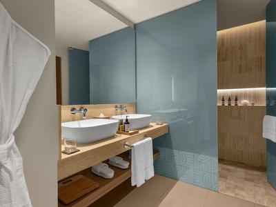 Modernes Badezimmer mit hellem Holz, großem Spiegel und weißem Waschbecken in klarem Design.