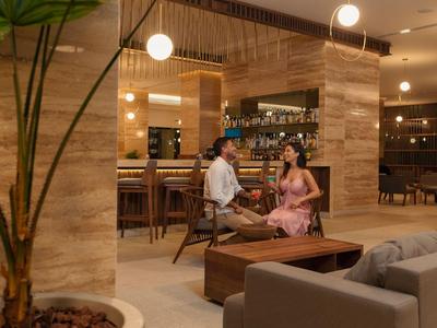 Ein Mann und eine Frau unterhalten sich in einem stilvollen Hotel-Loungebereich mit warmem Licht.