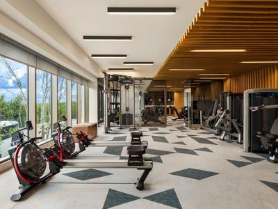 Palestra moderna con attrezzature e grandi finestre con vista.