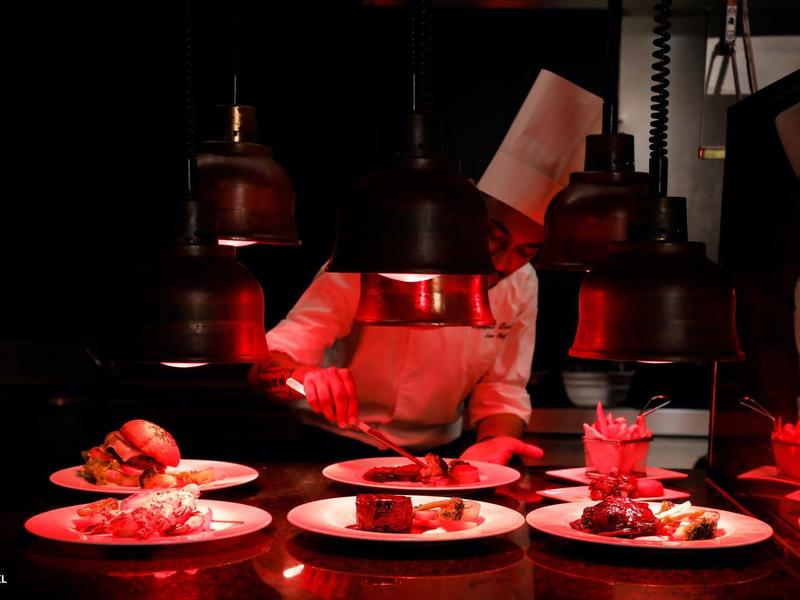 Szef kuchni sprawdza potrawy pod ciepłym oświetleniem w kuchni restauracji.