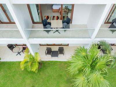 Balkony s posezením a stolem nad trávníkem s palmami před hotelem.