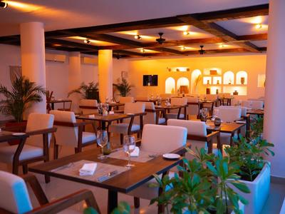 Pohodlná hotelová restaurace s dřevěnými stoly, pohodlnými židlemi a teplým osvětlením.