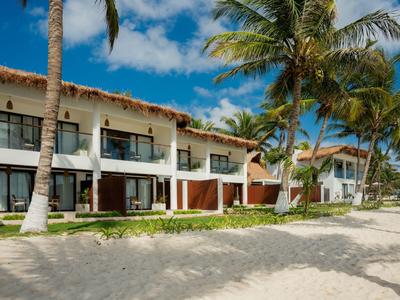 Reihenhaus-hotel am sandigen Strand mit Palmen und blauen Himmel.