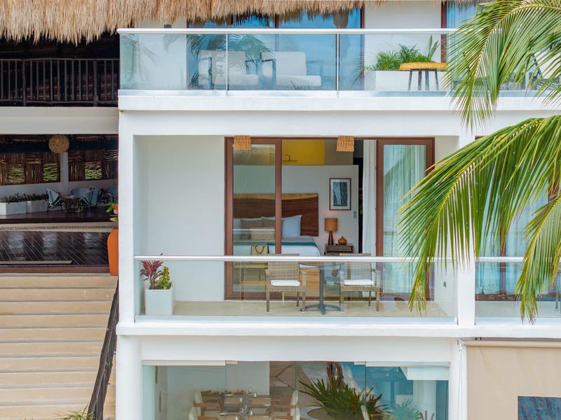 Moderní hotelový balkon se skleněnými dveřmi a výhledem na palmy