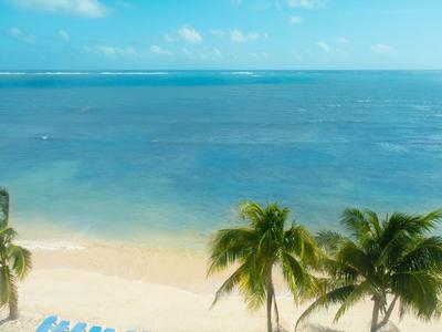 Vista di una spiaggia sabbiosa con palme e mare azzurro limpido sotto il sole.