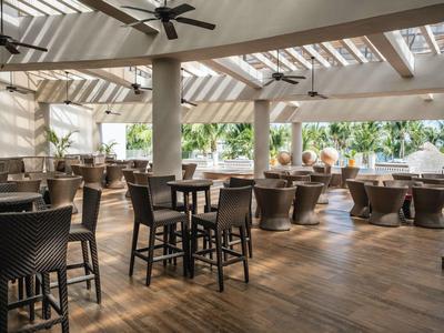 Ristorante luminoso e arioso con pavimento in legno e mobili scuri sotto i ventilatori a soffitto