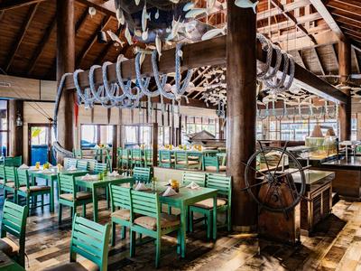 Ristorante luminoso con sedie verdi e decorazioni marine da uno scheletro.