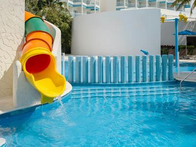 Uno scivolo d'acqua colorato sfocia in una piscina d'hotel blu chiaro.