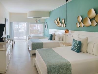 Moderne hotelkamer met twee tweepersoonsbedden, tv en grote glazen schuifdeur naar balkon