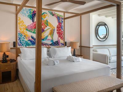 Camera d'hotel moderna con letto a baldacchino, arte murale colorata e decorazioni nautiche.