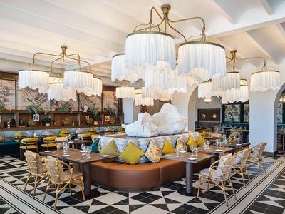 Luxurious hotel lounge with modern chandeliers, seating areas, and geometric floor pattern.