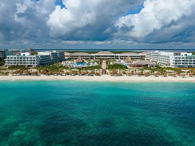 Luxury beach resort with white buildings, palm trees, and clear turquoise water.