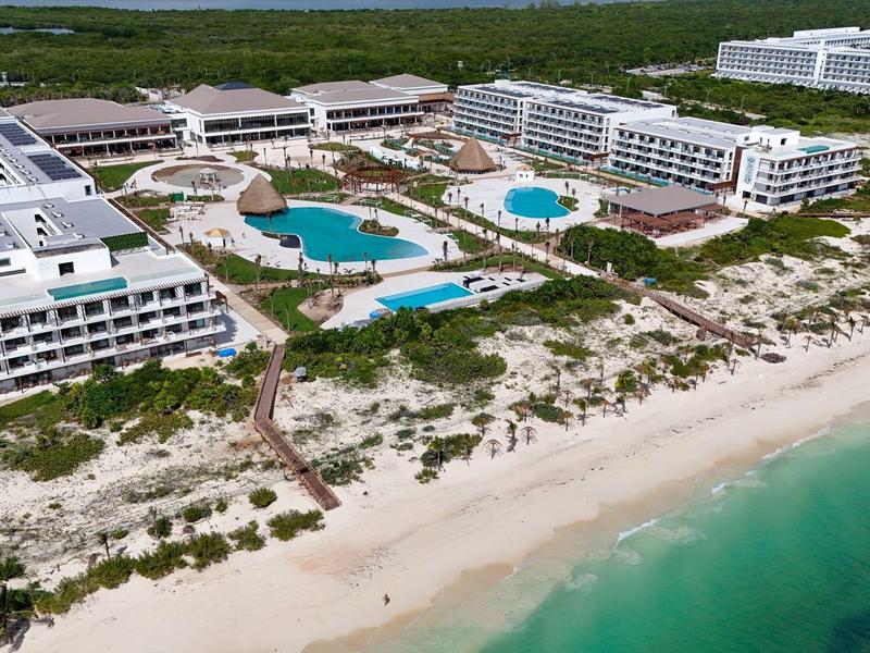 Grande resort sulla spiaggia con più edifici bianchi, piscine e accesso diretto al mare.