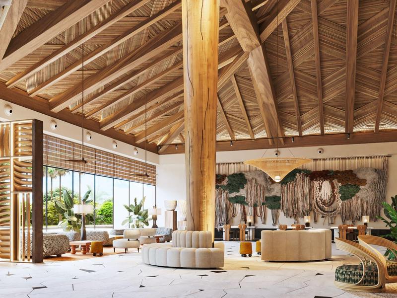 Zona lounge accogliente dell'hotel con travi in legno, divani e grandi finestre con vista su palme.