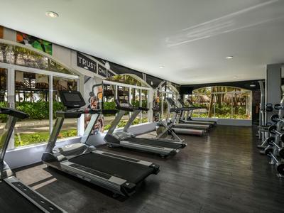 Světelné fitness s běžeckými pásy a výhledem na zahradu.