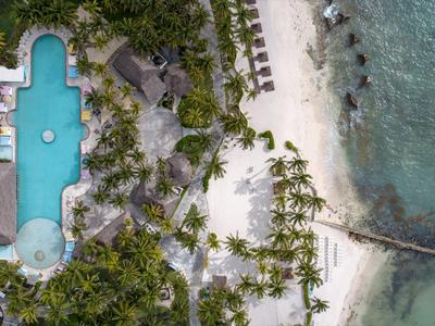 Letecký pohled na tropické středisko s velkým bazénem, palmami a pláží u moře