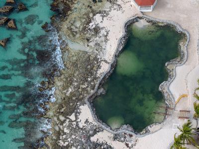 Letecký pohled na přírodní slanou vodní lagunu vedle moře na tropické pláži s palmami.