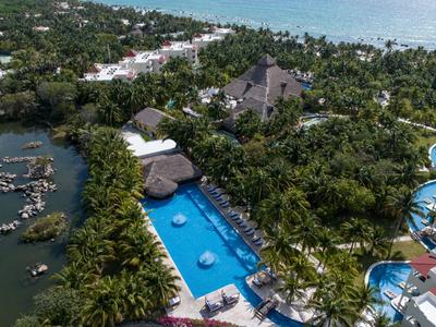 Letecký pohled na tropické letovisko s bazénem, palmami a přilehlým jezerem.