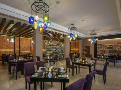 Elegant restaurant met paarse stoelen, moderne lampen en stijlvol gedekte tafels.