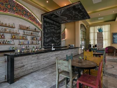 Accogliente bar d'hotel con lungo bancone, aree salotto e atmosfera decorativa.