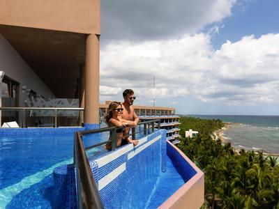 Coppia che si rilassa nella piscina a sfioro con vista sul mare in un hotel.