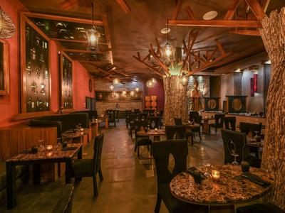 Ristorante accogliente con mobili in legno e tronchi d'albero come decorazioni in luce calda.