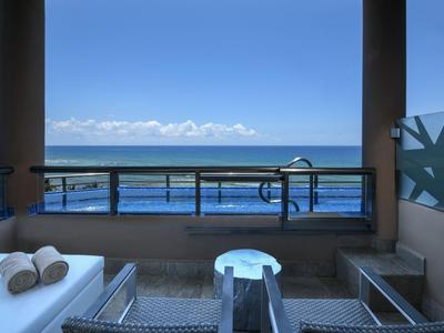 Balcone con due lettini, tavolo e vista limpida sul mare.