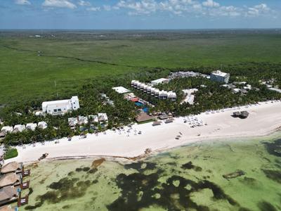 Vista aerea di un resort con edifici bianchi su una spiaggia tropicale con acqua turchese.