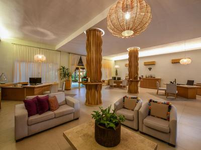 Hall di hotel luminosa e moderna con divani accoglienti e colonne di legno decorative.