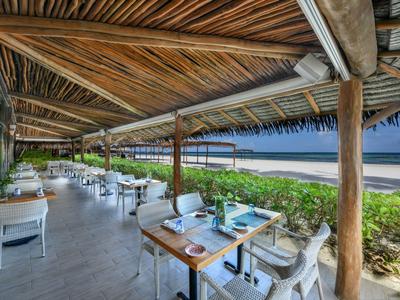 Ristorante all'aperto con tetto in legno con vista sulla spiaggia e sul mare.