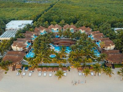 Vista aerea di un resort tropicale con più piscine e capanne sulla spiaggia sabbiosa