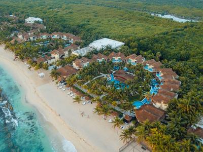 Vista aerea di un resort tropicale con spiaggia sabbiosa e vegetazione rigogliosa.