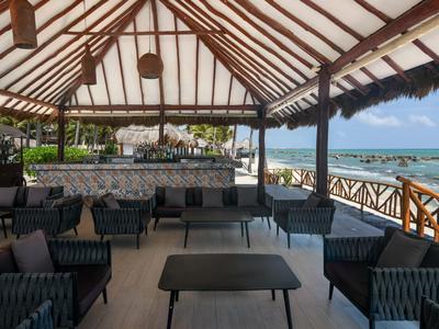 Offener Strandpavillon mit Sitzgelegenheiten und Blick auf das Meer bei klarem Himmel.
