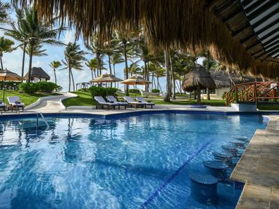Un'area piscina con lettini, palme e vista mare in un resort alberghiero.