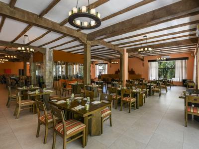 Ampia ed elegante area ristorante dell'hotel con soffitto con travi in legno e molti tavoli con sedie.