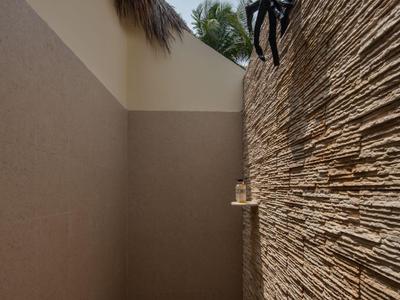 Corridoio esterno stretto con parete strutturata e figura decorativa in alto.