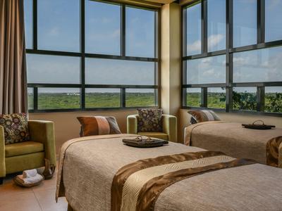 Camera d'hotel con due letti, una poltrona e grandi finestre con vista sul paesaggio.