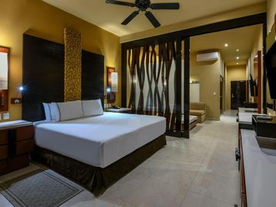 Camera d'hotel moderna con letto matrimoniale, mobili in legno e bagno sullo sfondo