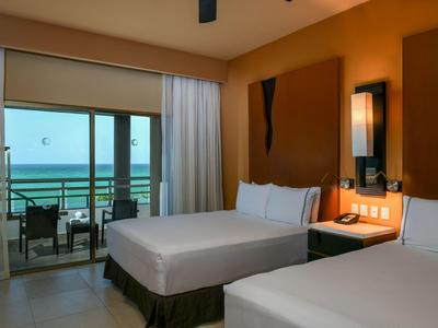 Camera d'hotel con due letti e vista sul mare tramite un balcone.