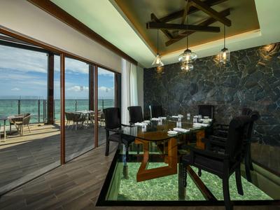 Jídelna se skleněným stolem a černými židlemi s výhledem na terasu a moře.