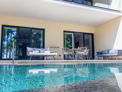 Moderner Außenbereich mit blauem Pool, grauen Sitzmöbeln und großem Fensterfront.