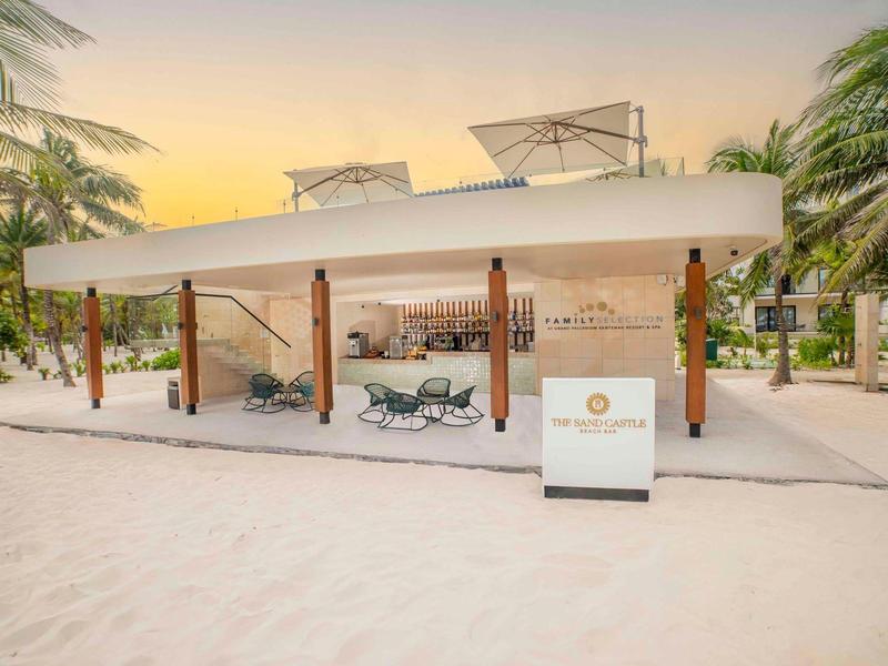 Padiglione aperto con sedie a sdraio su una spiaggia sabbiosa al tramonto.